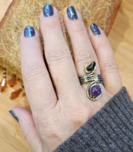 Tracy's Hand Wearing an Annealed Steel and Gold Wrapped Ring with Amethyst Beads